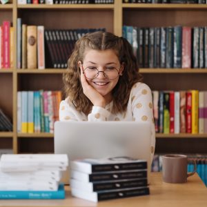 Girl studying among books using laptop